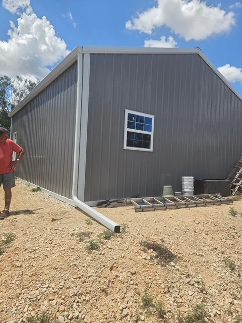 White gutter and downspout installed on a metal workshop