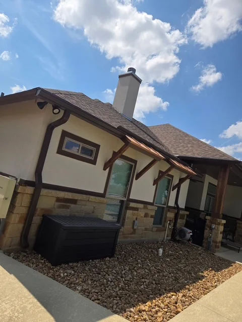 Brown seamless gutters installed by S&H on a Hill Country-style home