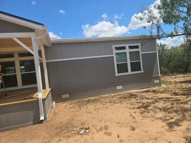White seamless gutter installed along a gray home addition
