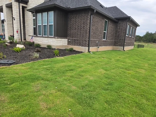 Dark seamless gutters installed around a brick home